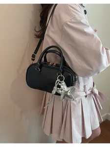 Detail shot of black leather Boston handbag with silver star pendant and crossbody strap.