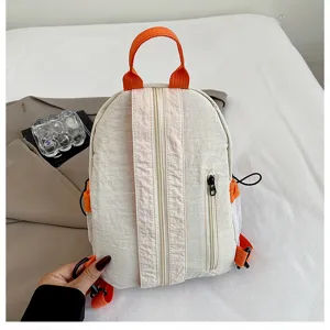 Detailed view of lightweight mini backpack in beige with vibrant orange straps and front zipper.