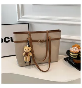 Detailed view of the beige and brown PU leather tote bag with a cute bear pendant charm.