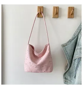 Pink star shoulder bag detail view, hanging on wooden hook with casual daily lifestyle setting.