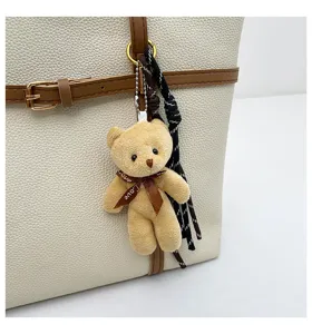 Chic women's tote bag detail featuring cute teddy bear pendant and woven charm for daily wear.