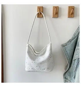 Close-up detail of white shoulder bag with silver star prints, hanging stylishly.