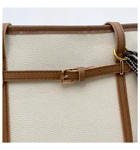 Detailed view of white and brown leather tote bag with stylish buckle and contrast trim.