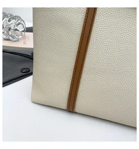Close-up detail shot of women handbag featuring beige litchi leather and brown stripe trim.