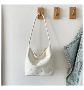 White shoulder bag detail with silver star pattern hanging on wall hook interior display.