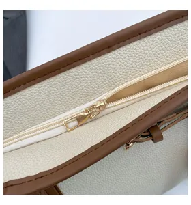 Close-up detail of women's contrast color tote bag zipper, fine stitching and premium leather.