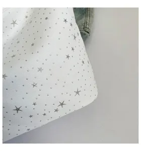 Close-up detail of white canvas shoulder bag featuring stylish silver star studs and dots.