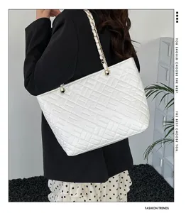 Vista dettagliata dell'elegante borsa tote trapuntata bianca con tracolla a catena.