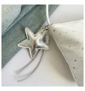 Detailed view of the stylish white star print shoulder bag featuring a chic silver star pendant.