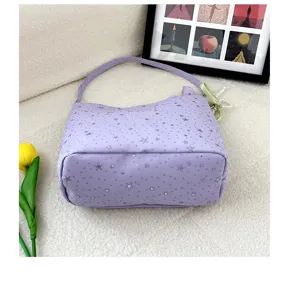 Close-up detail of the purple star print shoulder bag fabric and cute pearl bow pendant.