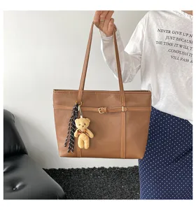 Brown PU leather tote bag with teddy bear charm and shoulder straps, detailed design for daily wear.