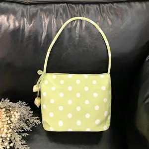 Closeup of green polka dot shoulder underarm bag with bow detail, stylish casual handbag.