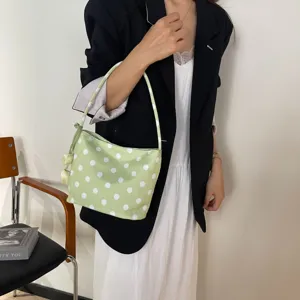 Close-up detail of a light green polka dot shoulder underarm bag worn with casual outfit.
