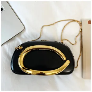 Gros plan sur le détail du sac de soirée noir avec un anneau en métal doré unique.