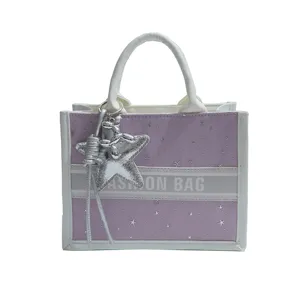 Purple star embroidered canvas tote bag with white leather handles and stylish star charm pendant.