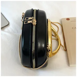 Vue de detail d'un sac bandouliere rond noir chic avec une poignee doree et chaine.