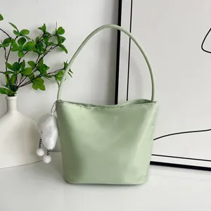 Primer plano detallado del bolso de hombro de nailon verde claro con peluche y estilo.