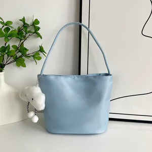 Vista detallada del bolso de hombro de nylon azul con bonito colgante de peluche de nube.