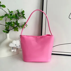 Primer plano del bolso de hombro de nailon rosa vibrante con lindo colgante de felpa.