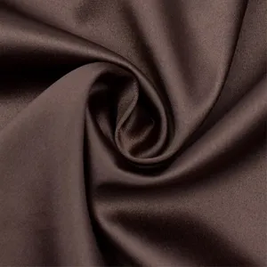 Primo piano dettaglio tessuto satin marrone con consistenza liscia ed elegante drappeggio.