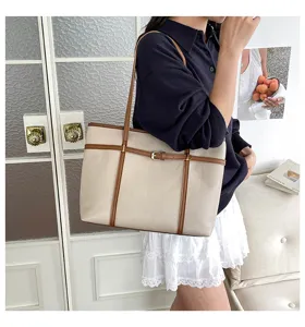 Close-up scene of a stylish beige tote bag with brown straps worn by a model indoors.
