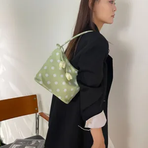 Green polka dot underarm shoulder bag detail showing stylish fabric and cute flower accent design.