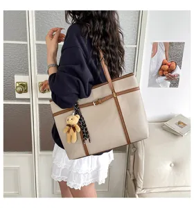 Detail view of casual large capacity tote bag with cute bear charm and brown leather trim.