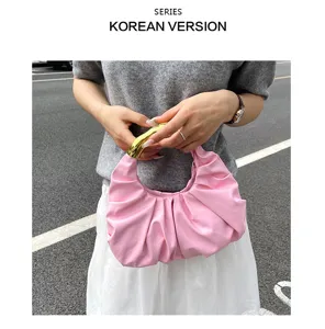 Detailaufnahme der rosa gerafften Handtasche mit elegantem metallic goldenen Griff.