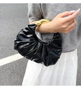 Detailansicht der schwarzen plissierten Abendtasche mit elegantem goldenen Metallgriff.