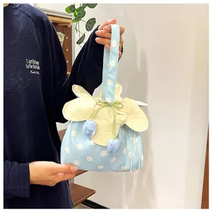 Dettaglio in primo piano di una borsa in tessuto floreale dolce con pois e ciondoli a tulipano.