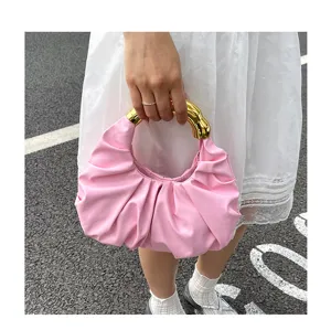Detailaufnahme der pinken plissierten Handtasche mit edlem goldenem Metallring als stilvoller Griff.