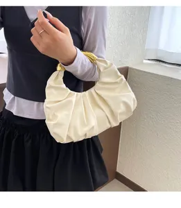 Detailansicht der cremeweißen plissierten Handtasche mit elegantem goldenem Griff.
