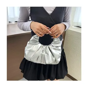 Nahaufnahme der silbernen Plissee-Handtasche mit stilvollem Metallring-Griff, schickes Detail.