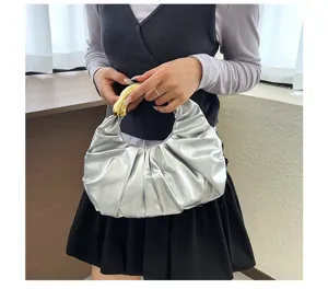 Elegante silberne plissierte Handtasche mit Metallgriff, modisches Abendtaschen Detail.