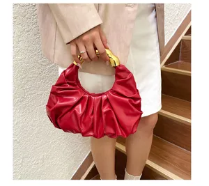 Detailansicht der roten gefalteten Handtasche mit edlem goldenen Metallgriff für Damen.