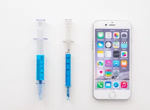 Gedetailleerd overzicht van creatieve spuit markeerstift met blauwe inkt en schaal naast telefoon.