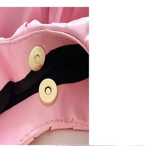 Detailaufnahme der pinken gerafften Handtasche mit Magnetschnalle, feine Verarbeitung.