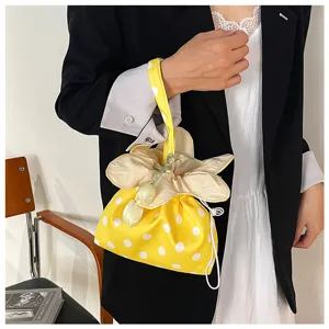 Primo piano di una borsa in tessuto a pois gialli con coulisse a fiore, elegante.