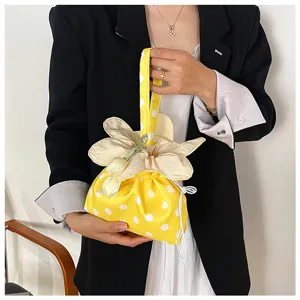 Primo piano della borsa in tessuto a pois gialli con un design a coulisse a forma di fiore.