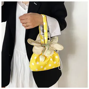 Primo piano sul manico della borsa in tessuto a pois gialli con dettaglio di fiore e coulisse.