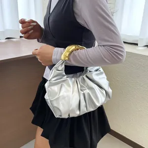 Elegante silberne geraffte Handtasche für Damen mit goldenem Griff und modernem Knödelstil.