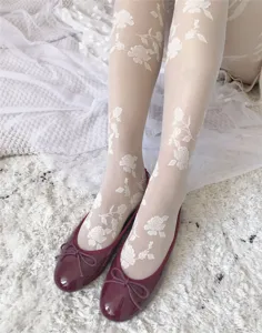 Detail view of women white sheer pantyhose featuring delicate rose floral embroidery patterns.