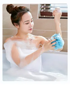 Detailed view of a soft blue mesh bath sponge used during a relaxing body wash routine in a tub.