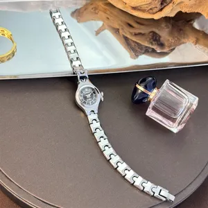 Exquisite small dial quartz watch with delicate slim silver strap, elegant women's detail shot.