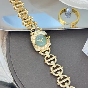 Detailaufnahme der goldenen Kettenglieder-Uhr mit quadratischem grünem Zifferblatt und Ziffern.