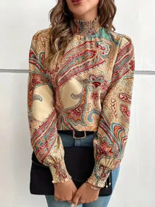 Detailed shot of a stylish women's high-neck smocked paisley print long sleeve blouse.