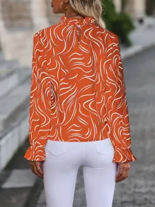 Detailed view of women's orange abstract print long sleeve blouse with ruffled mock neck.