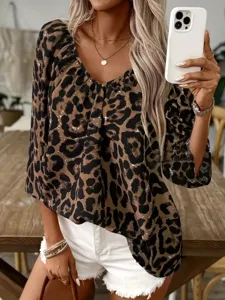Detailed shot of a stylish V-neck leopard print blouse worn by a model in a casual setting.