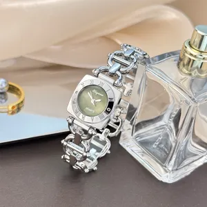 Nahaufnahme einer eleganten Quarzuhr mit quadratischem grünem Zifferblatt und Metallarmband.