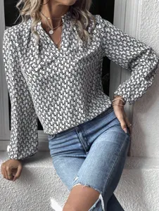 Detailed view of women's black and white abstract print pleated V-neck lantern sleeve blouse.